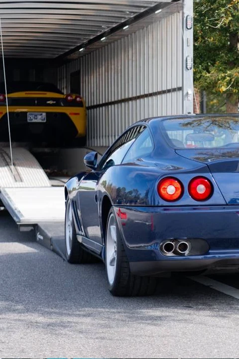 Sports cars beside and inside an enclosed transport trailer.