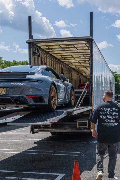 Sports car on a loading ramp at an enclosed transport trailer.