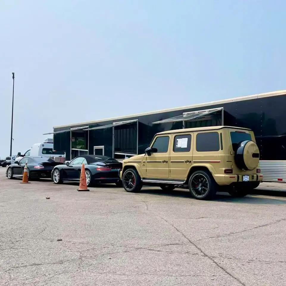 Cars and an SUV beside an enclosed car carrier.