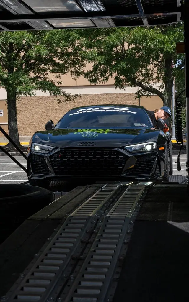 A dark car inside an enclosed trailer.