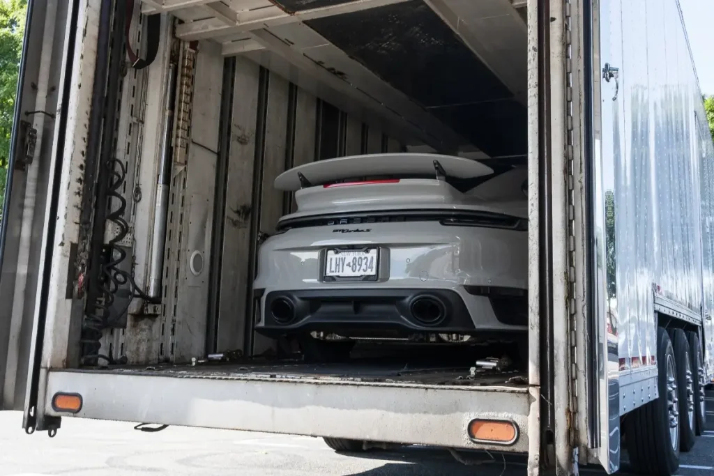 A white car in a carrier truck.