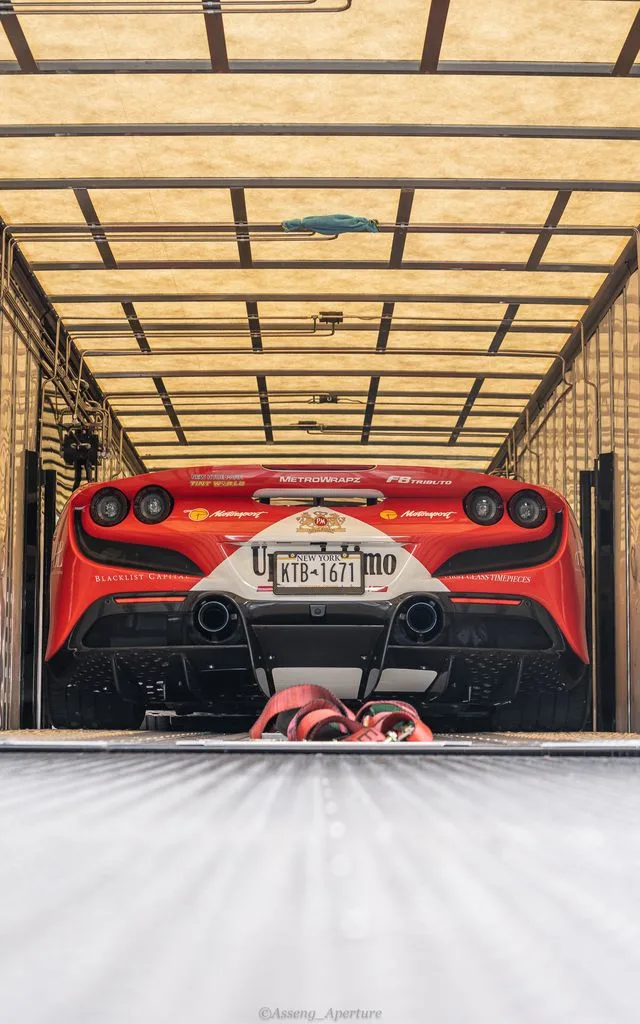 A red sports car inside a covered carrier.