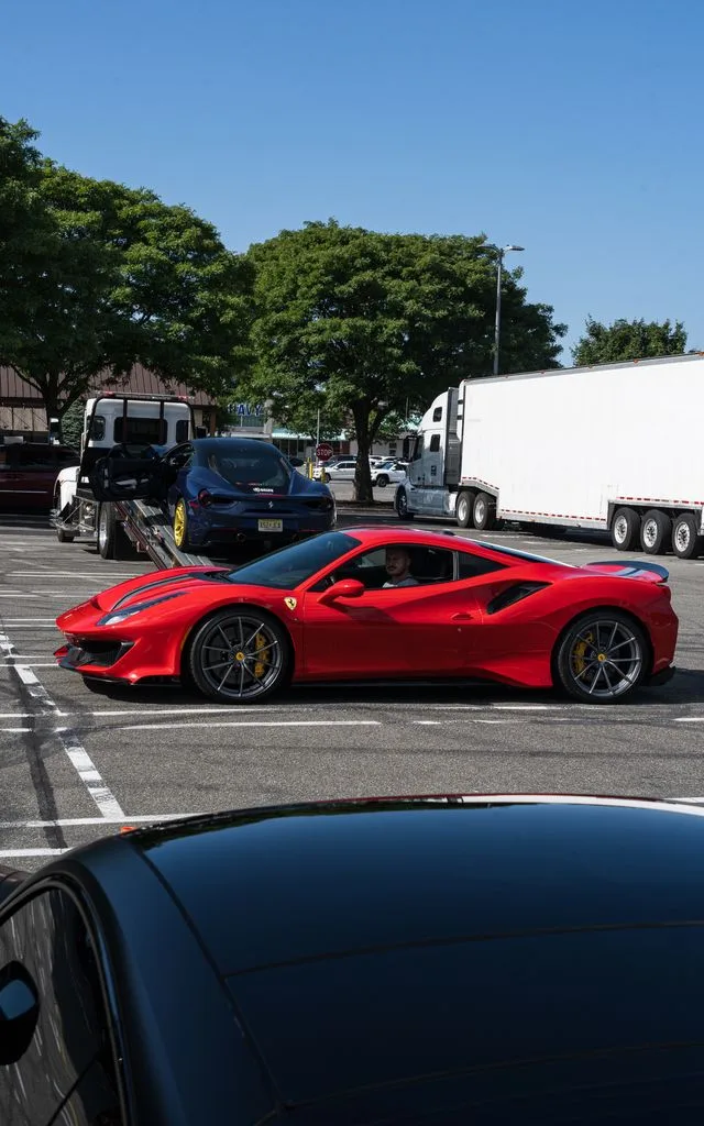 A red sports car beside a transport trailer.