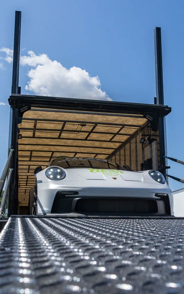 A white sports car at the top of a trailer ramp.